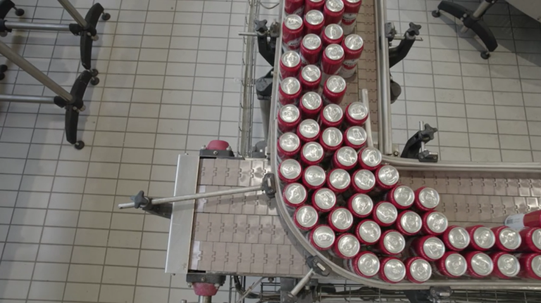 Beer bottles move in order on factory conveyors.