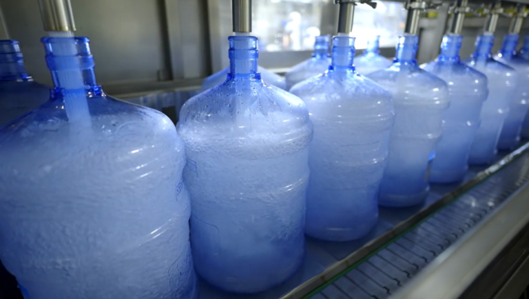 Plastic Buckets Aligned on a Conveyor Belt for Filling